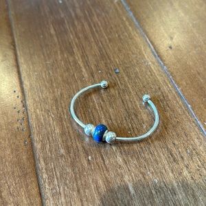 Silver cuff bracelet with blue bead.